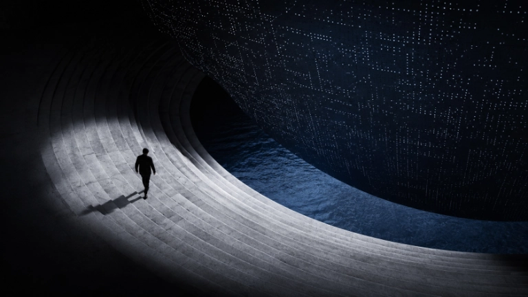 AI creativity represented by a lone figure moving beneath a vast computational structure in a dark architectural space